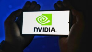 Hands holding a smartphone showing the NVIDIA logo on a bright screen.